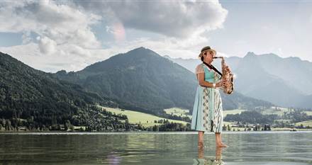 Frau steht auf einem See und spielt Saxophon